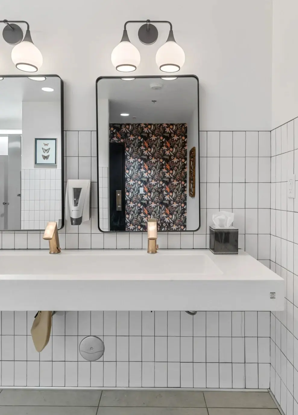 Floating restroom vanity with white tile and black-framed mirror