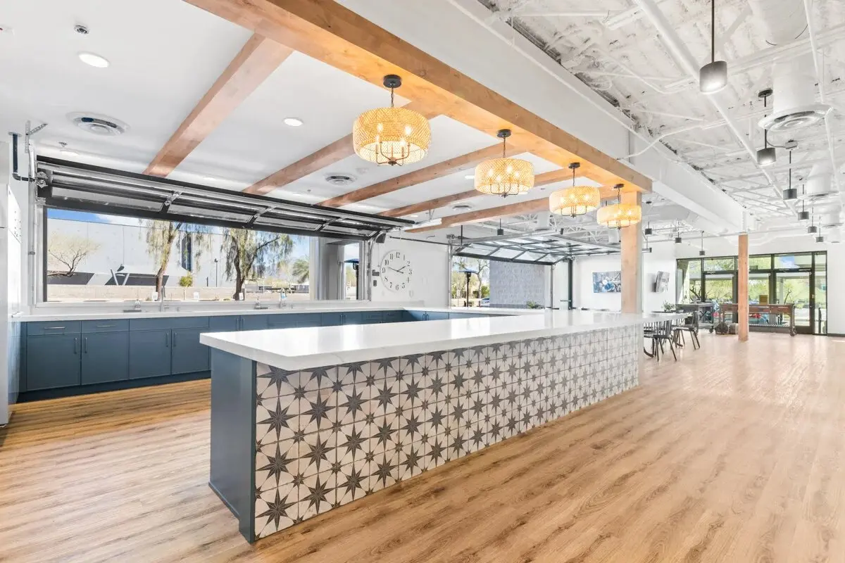 Long hospitality kitchen island beneath woven pendant lighting