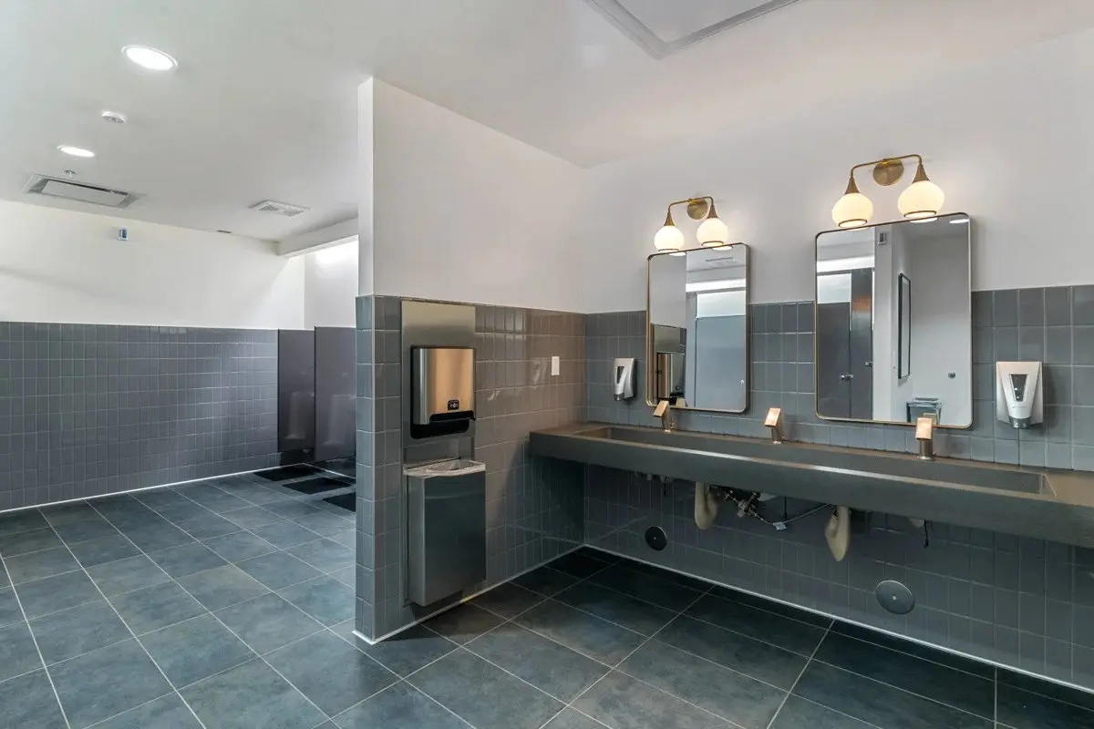 Renovated church restroom with dark tile and coordinated vanities